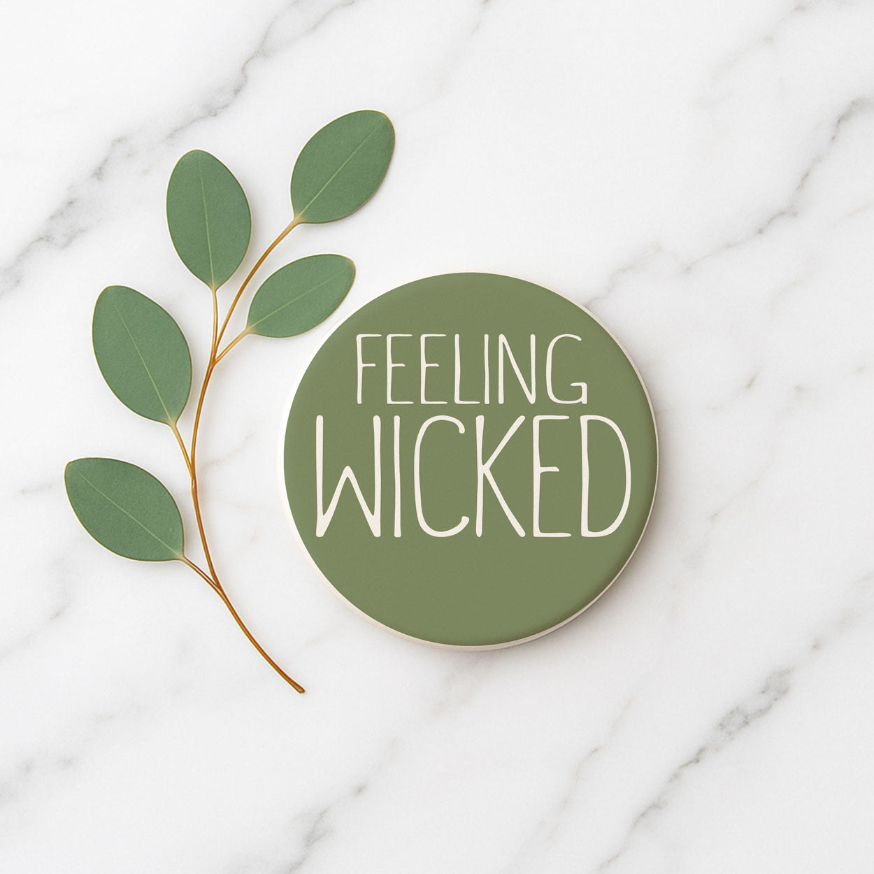 Green circular sign with 'FEELING WICKED' text on a marble background