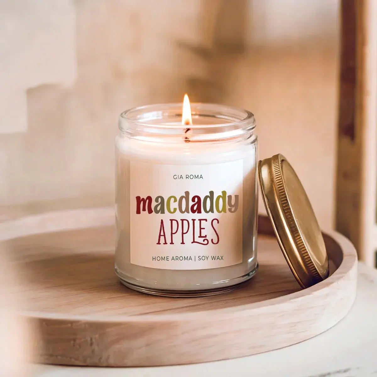 Candle labeled 'macdaddy APPLES' on a wooden surface with a blurred background