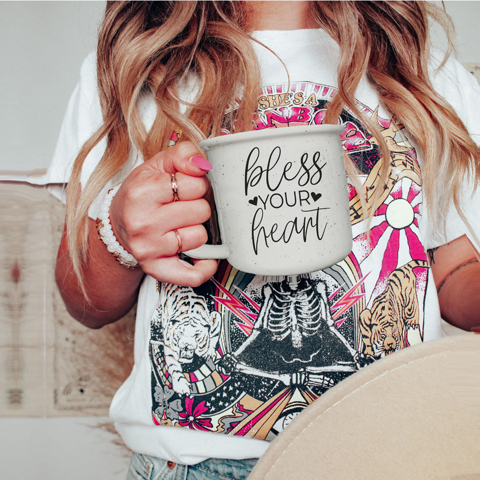 Person holding a mug with 'bless your heart' text, wearing a colorful shirt.