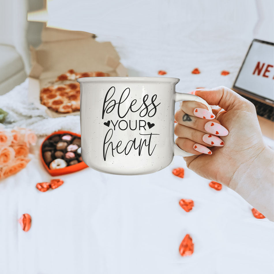 Hand holding a mug with 'kisses 25 cents xoxo' text on a table with snacks and flowers.