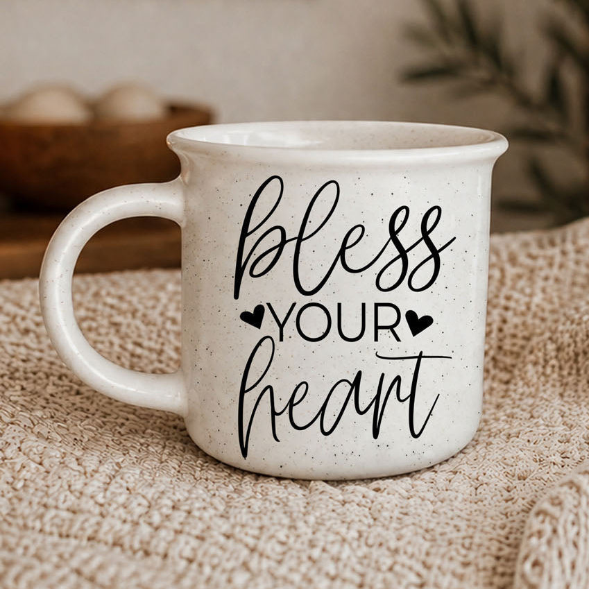 White mug with 'bless your heart' text on a textured surface