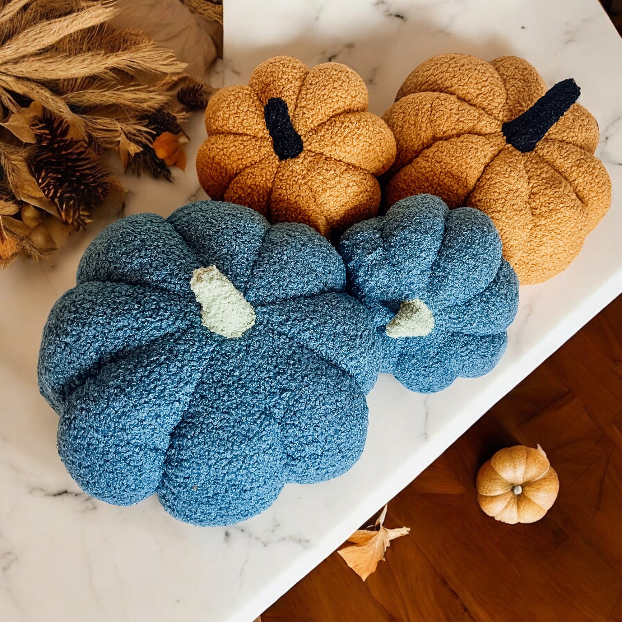 Decorative pumpkins in blue and orange on a marble surface with a wooden floor.