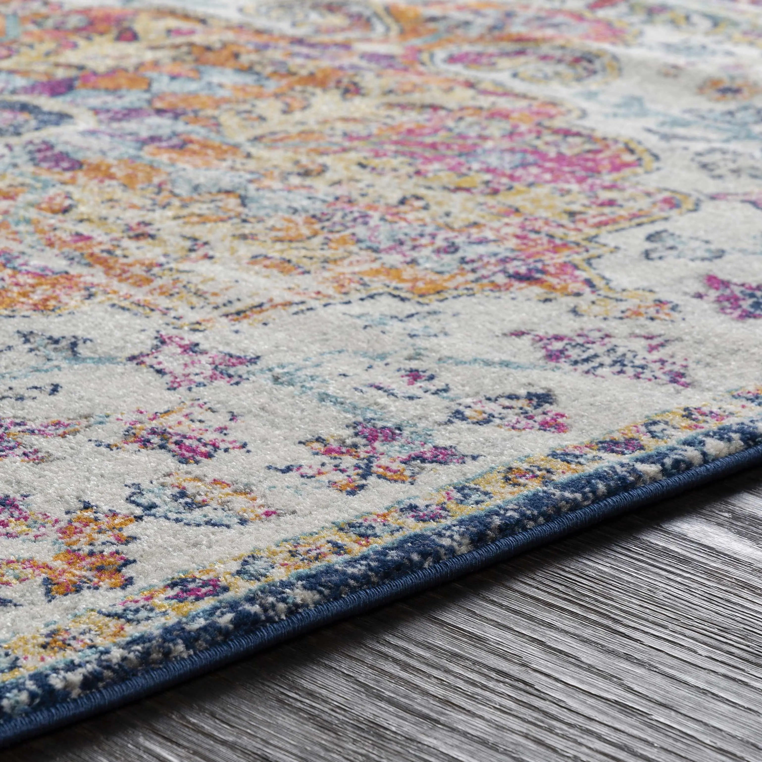 Cozy farmhouse-style area rug with colorful floral patterns and blue border on wood floor