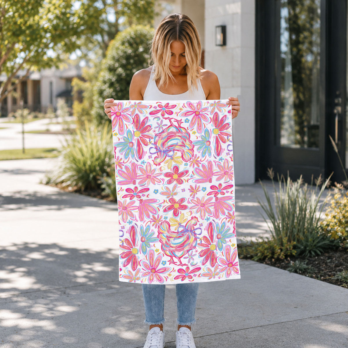 Woman holding a colorful floral towel outdoors.