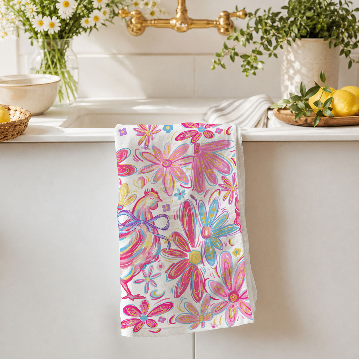 Colorful floral towel hanging on a kitchen towel rack with a sink and plants in the background.