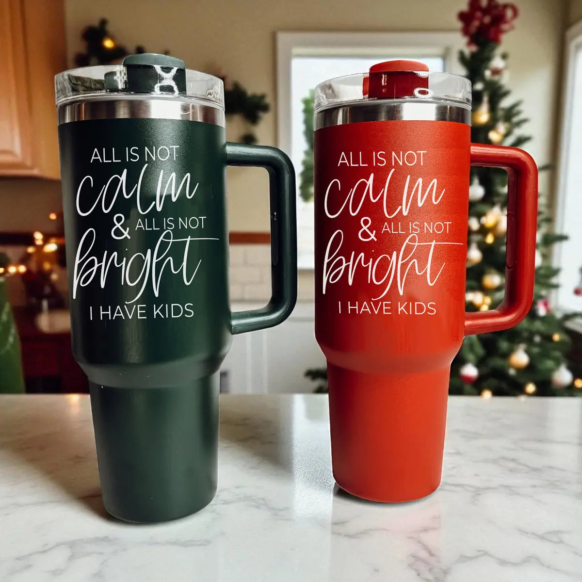 Two tumblers, one green and one red, with humorous text on a kitchen counter.