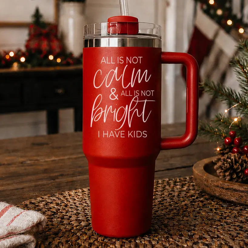 Red tumbler with humorous text on a table with Christmas decorations