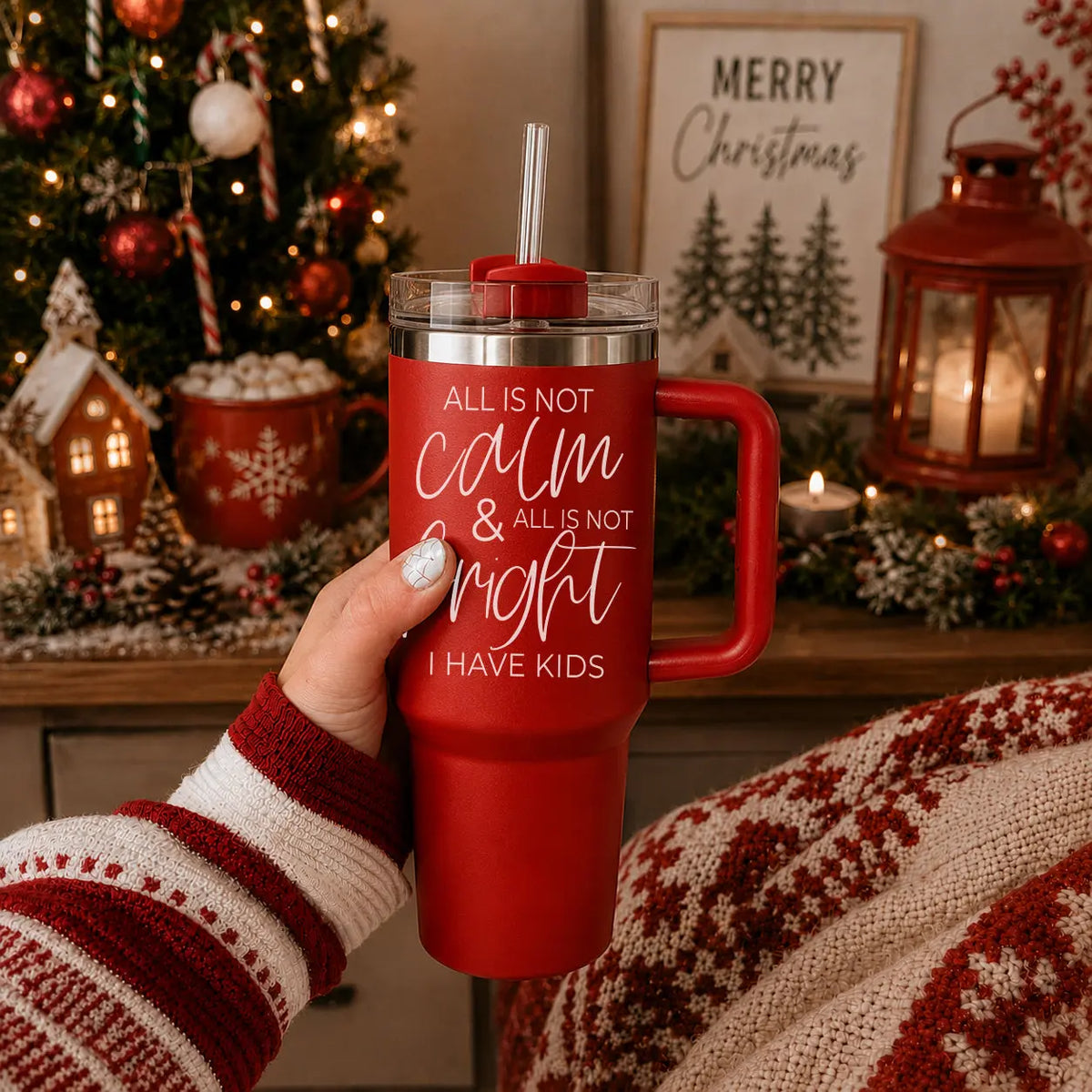 Red tumbler with humorous text held in front of a Christmas-themed background