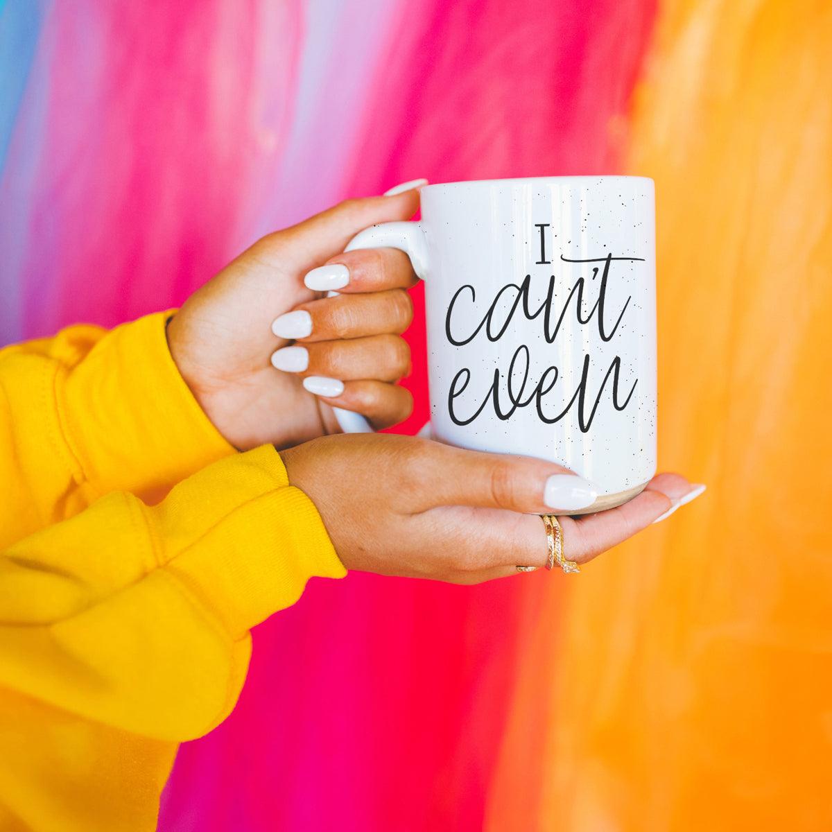 Person holding a white mug with 'cat mom' text against a colorful background
