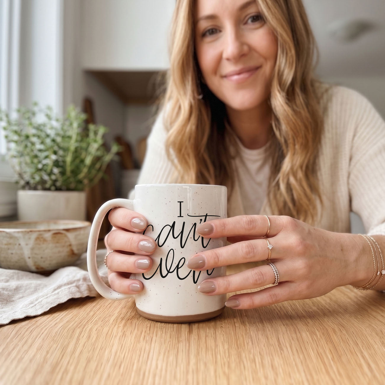 Woman holding a mug with 'I can't even' text in a home setting