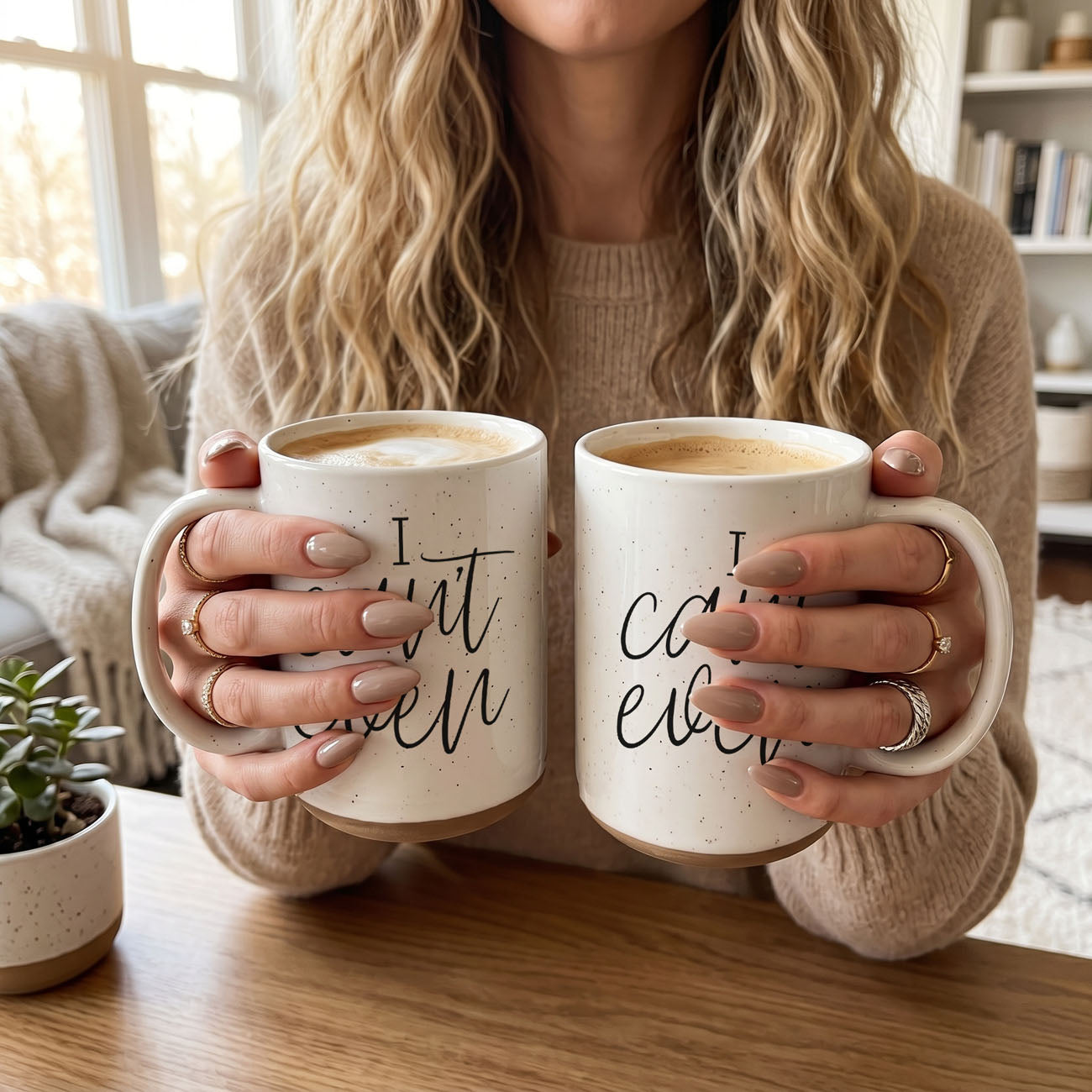 Person holding two mugs with coffee, one mug has text on it.