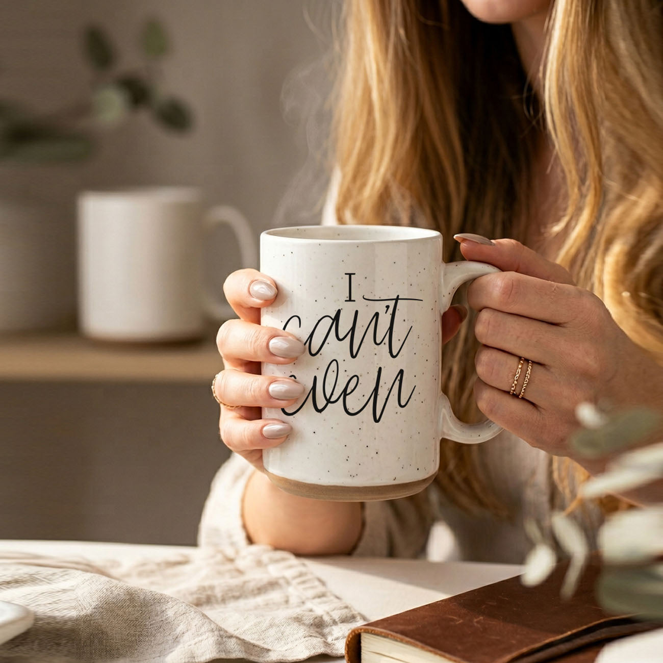 Person holding a mug with 'I can't even' text in a cozy indoor setting.
