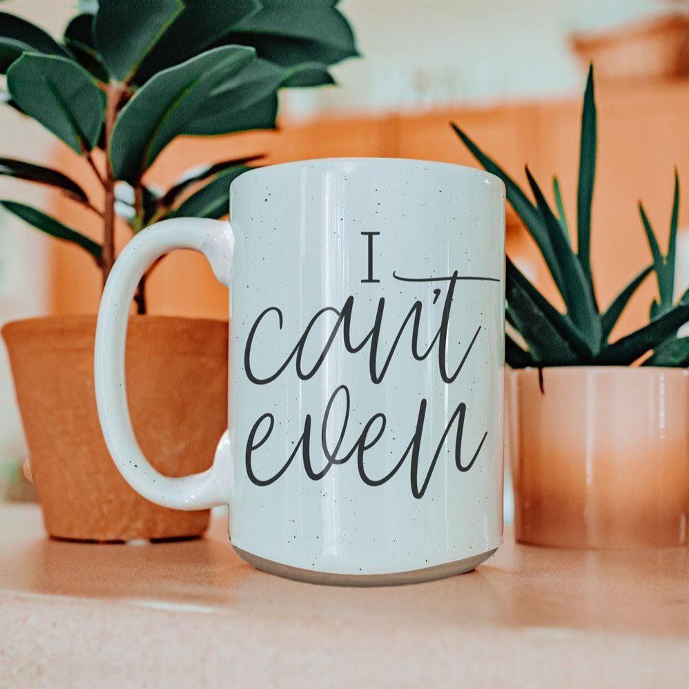 White mug with 'I can't even' text in a home setting with plants