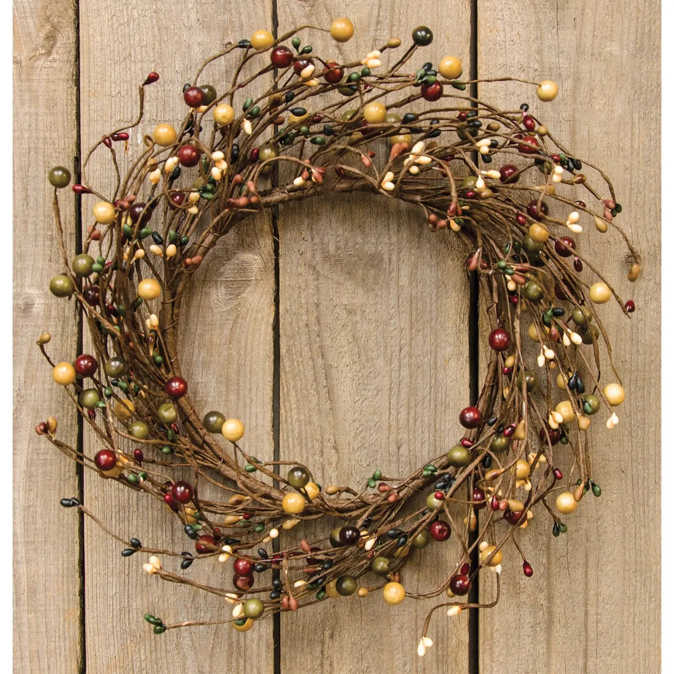 A rustic twig wreath decorated with small berries in red, gold, and green, with tiny warm white fairy lights, shown against a vertical wood plank background.