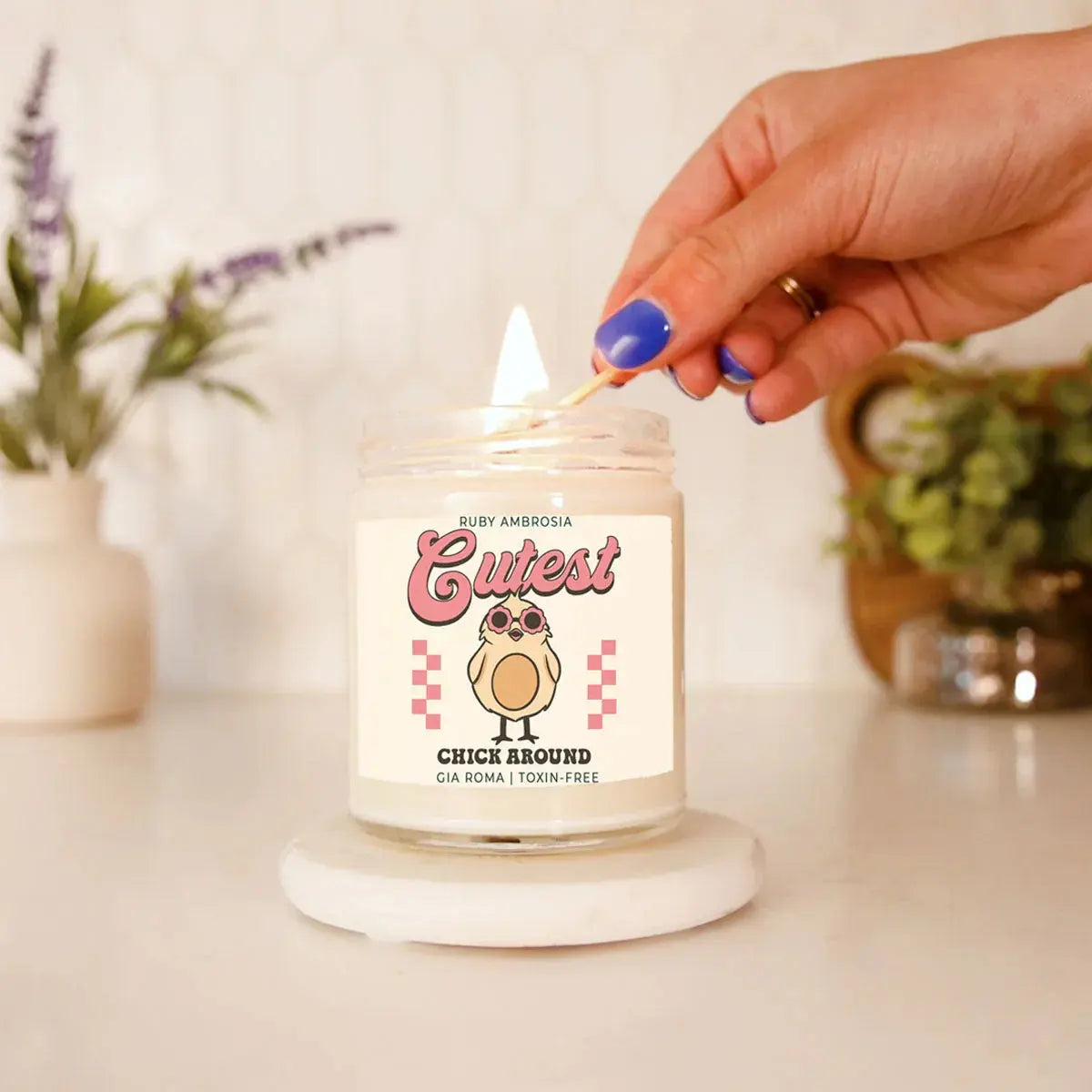 Candle being lit with a decorative label featuring a cartoon chick, on a neutral background.