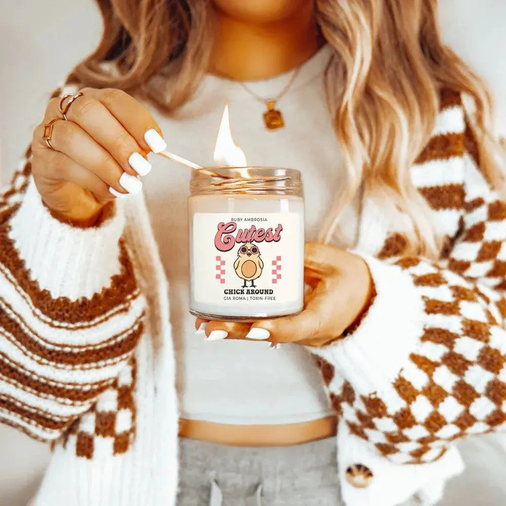 Person lighting a candle labeled 'Cutest Chick Around' with a checkered design.
