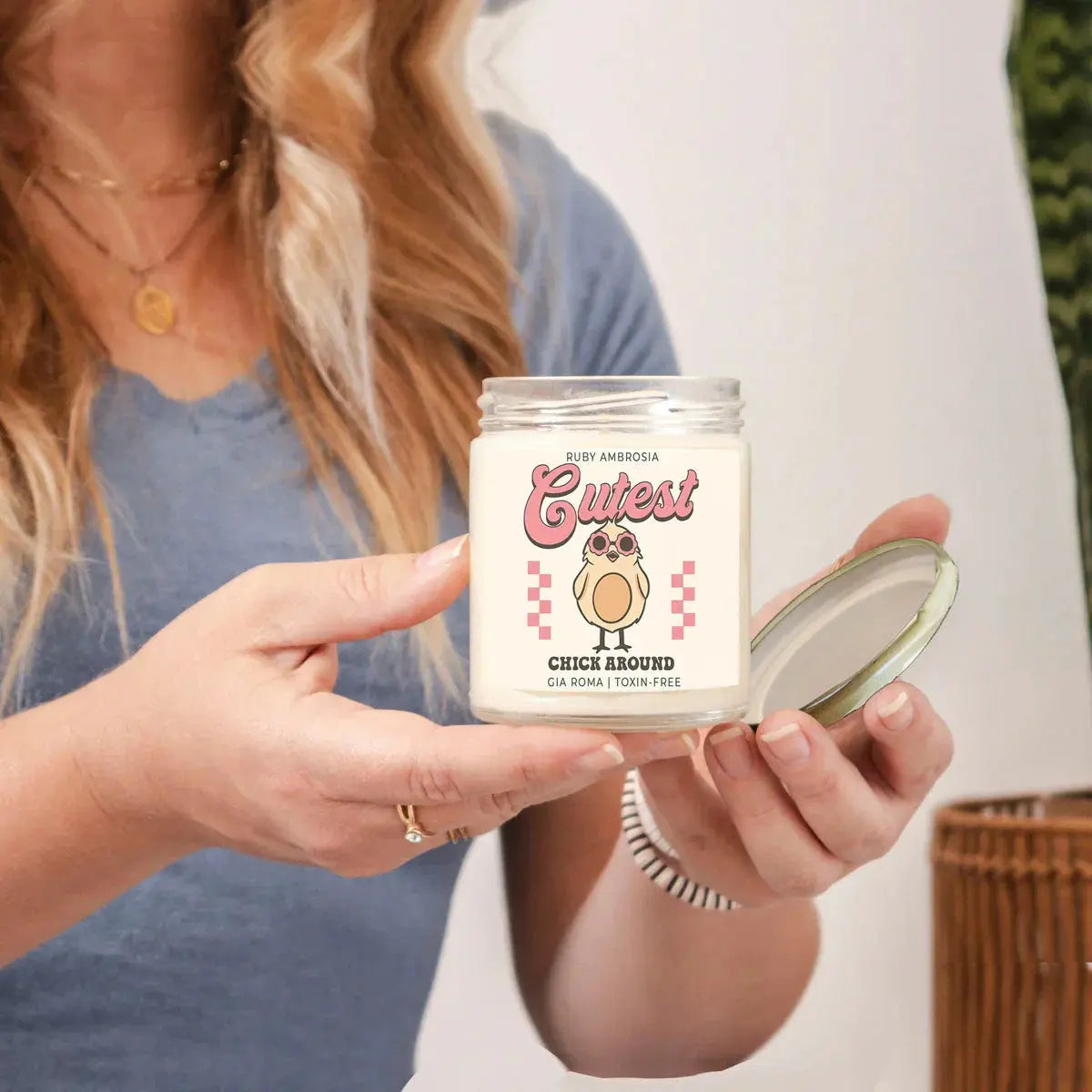 Person holding a candle jar with a cute owl design and text.