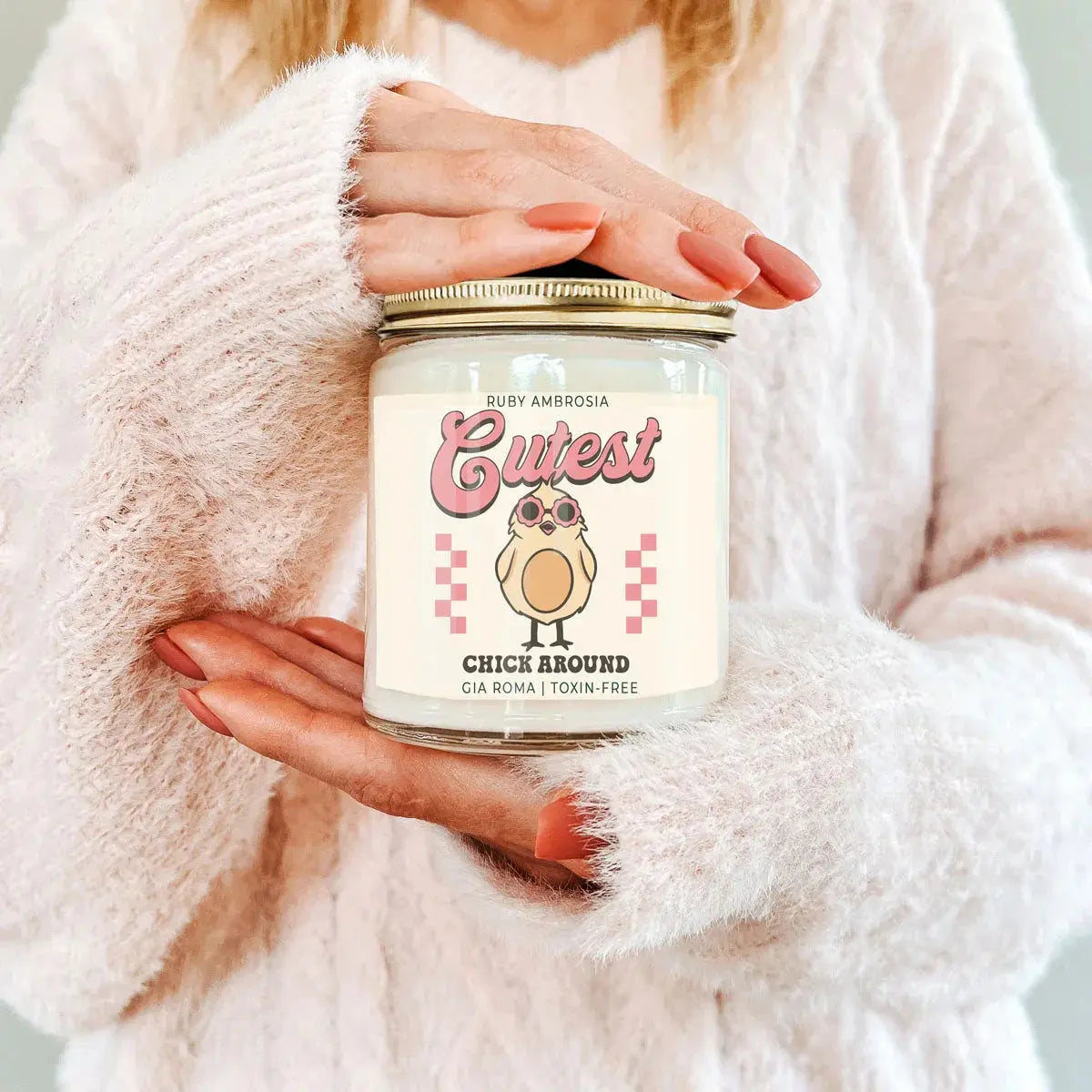 Person holding a candle labeled 'Cutest Chick Around' with a cartoon chick design.