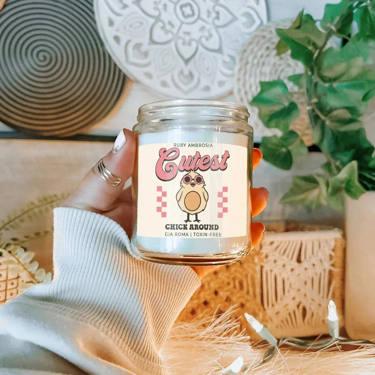 Hand holding a candle labeled 'Cutest Chick Around' with decorative background