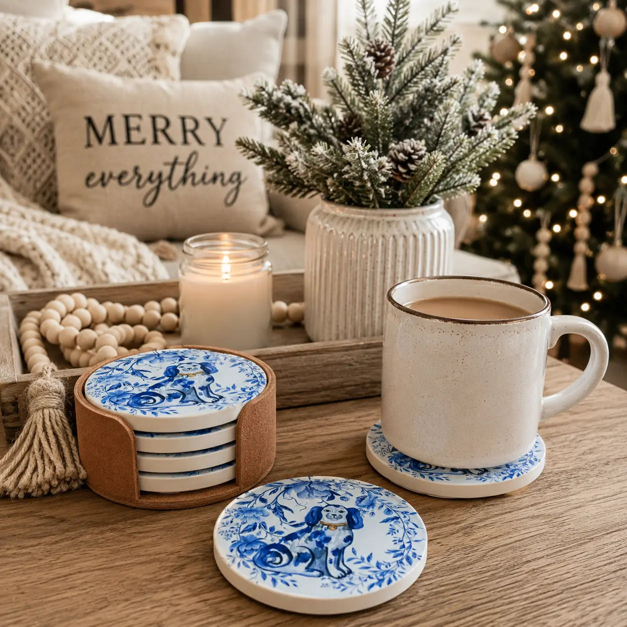 Blue and white ceramic coasters with a classic dog illustration pattern, shown in a cozy holiday setting with a mug, candle, and decorative pillows.