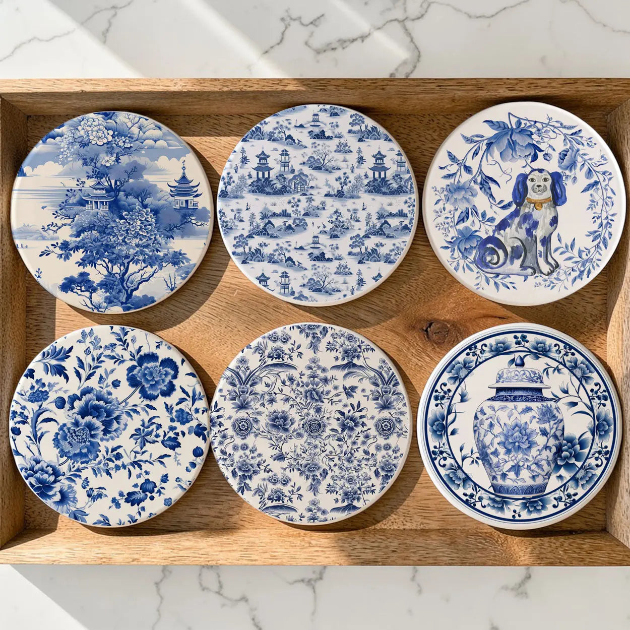 Set of six blue and white ceramic coasters with various designs on a wooden tray.