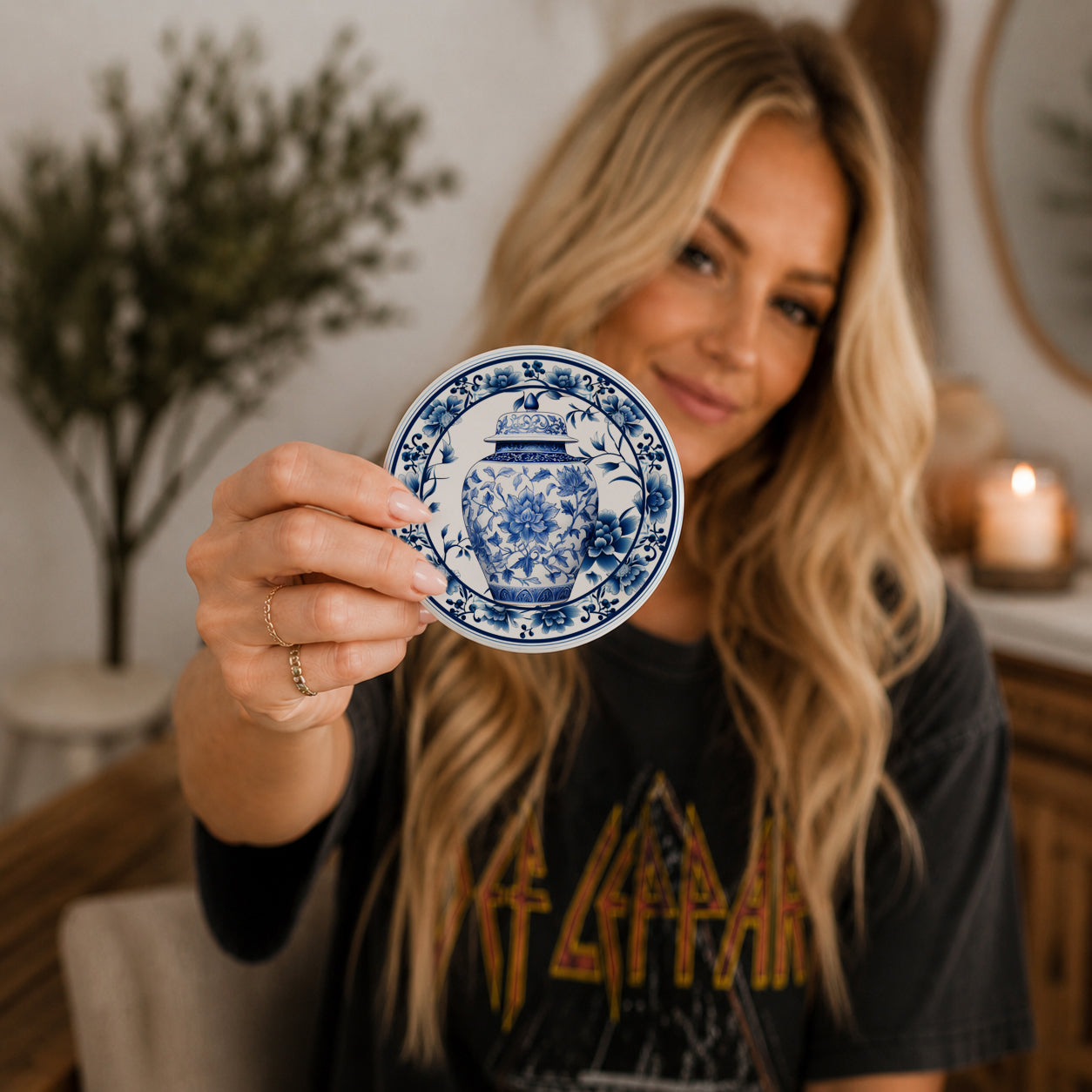 Woman holding a blue and white decorative coaster in a home setting
