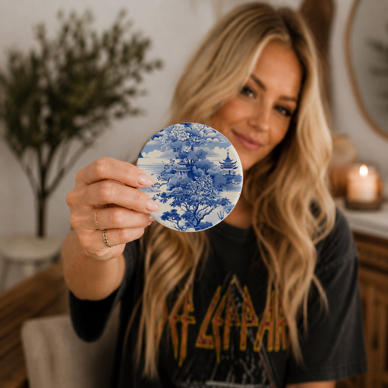 Woman holding a circular blue and white patterned coaster in a home setting