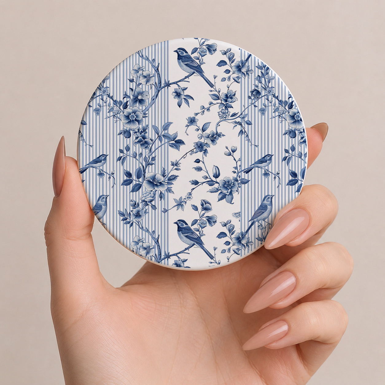 Round coaster with blue floral and bird pattern held by a hand against a beige background
