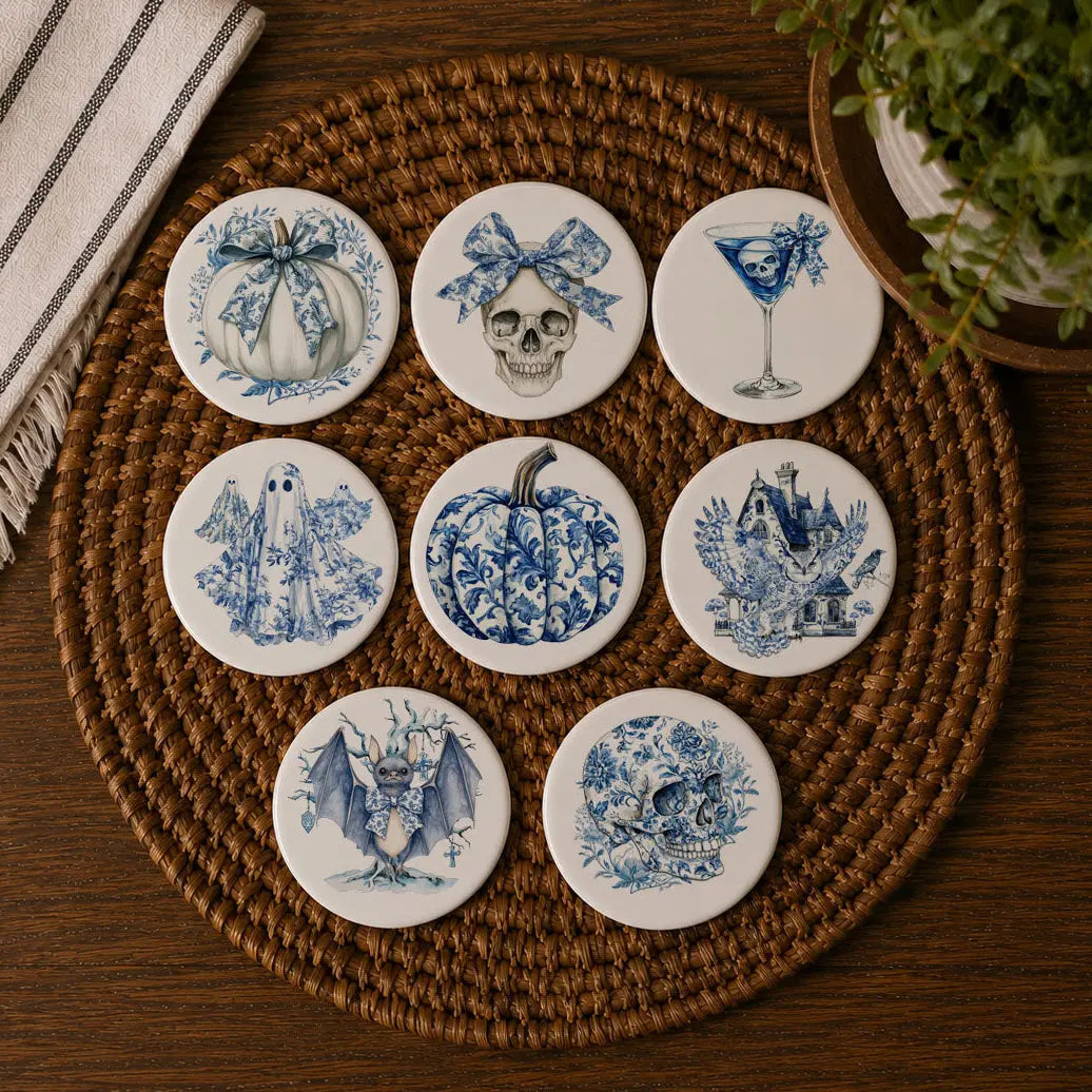 Set of blue and white ceramic coasters with Halloween-themed designs on a woven mat.