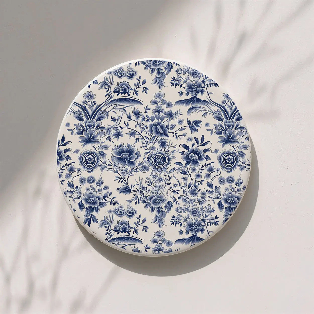 Round ceramic coaster with blue floral pattern on a white background