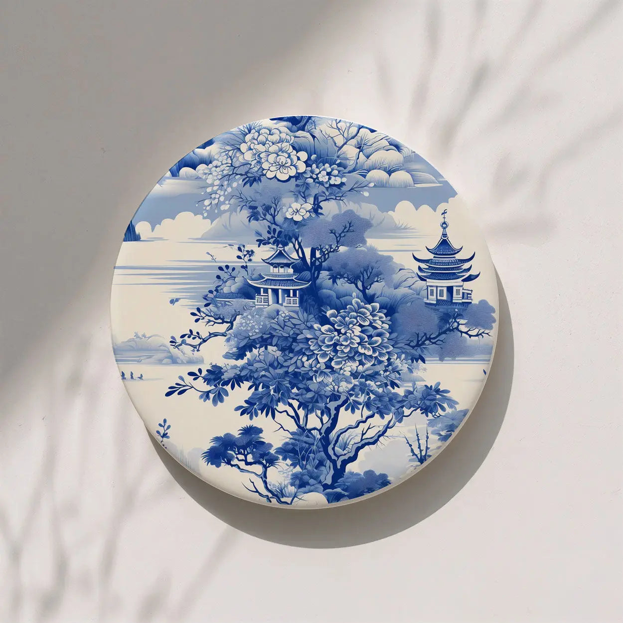 Round ceramic coaster with blue floral and architectural design on a white background