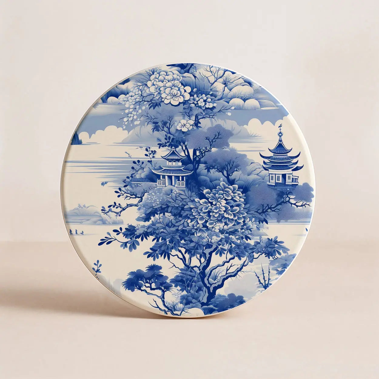 Round ceramic coaster with blue and white floral and architectural design on a beige background
