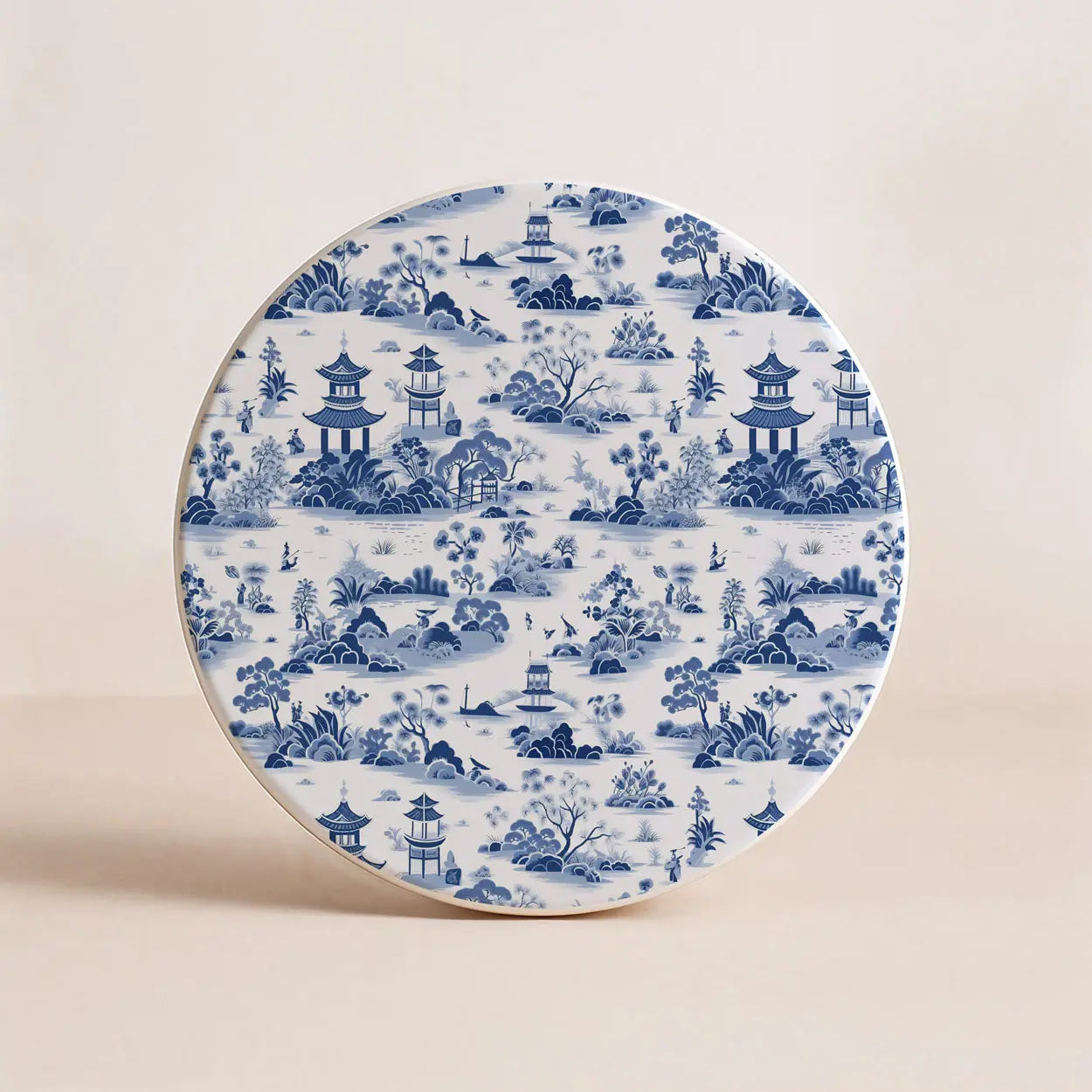 Decorative coaster with blue and white landscape design on a beige background
