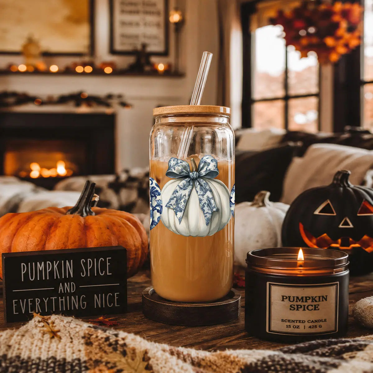 Glass jar with pumpkin spice drink, decorative bow, and pumpkin spice candle in a cozy autumn setting.