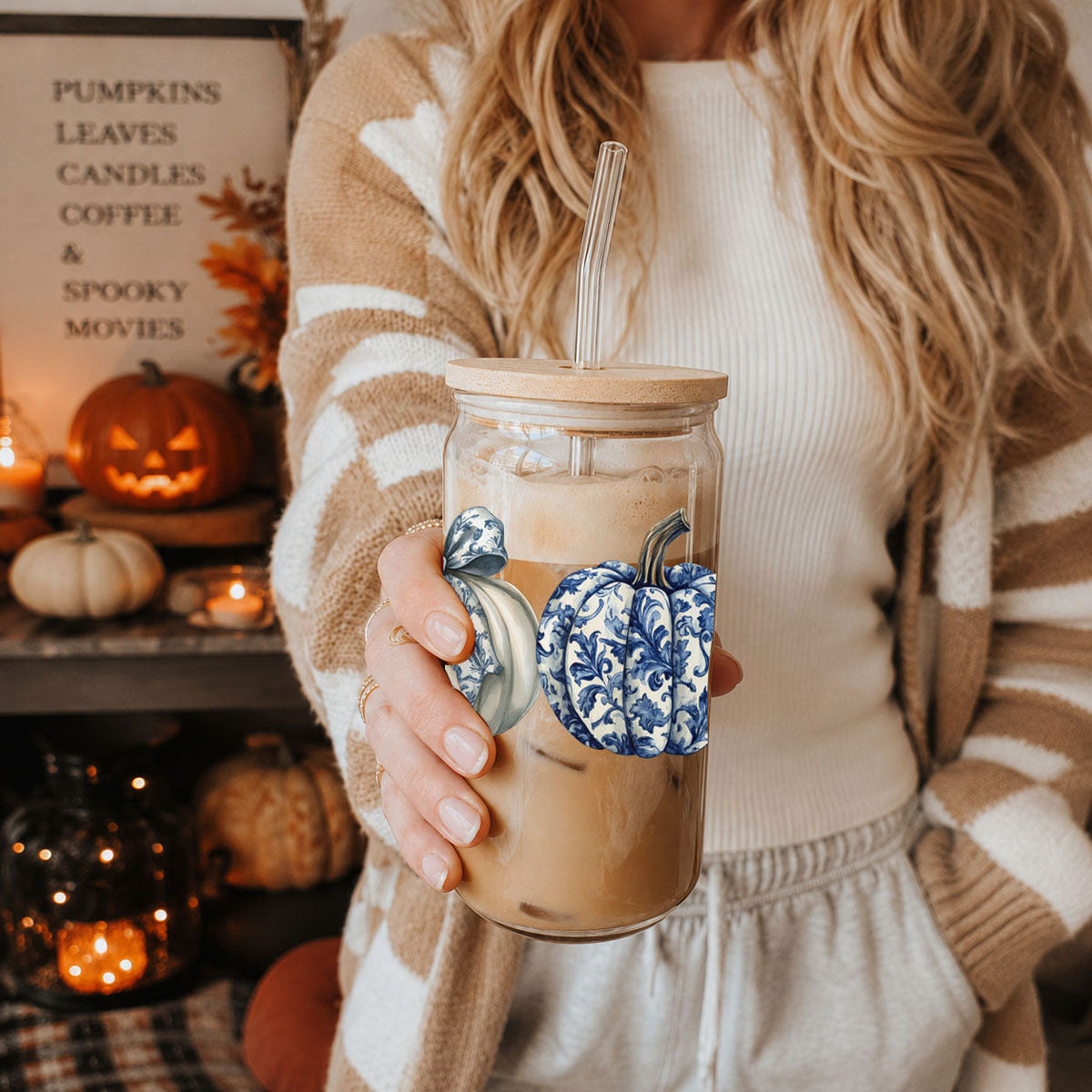 Person holding a coffee mug with decorative pumpkins in a cozy autumn setting.