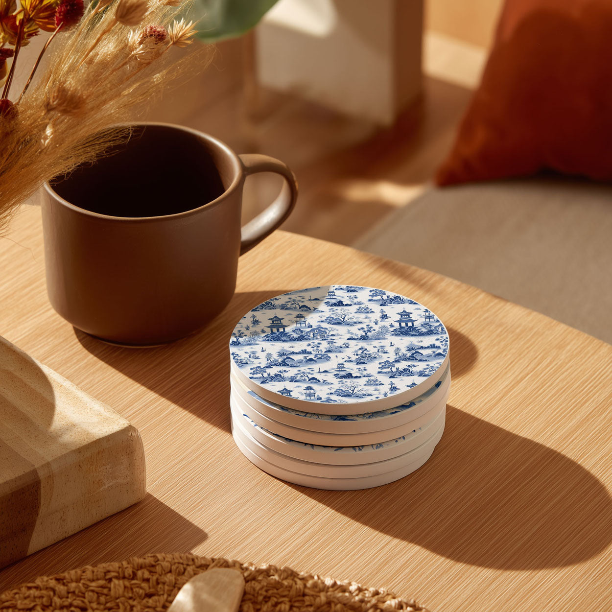 Stack of blue and white patterned coasters on a wooden table with a brown mug.