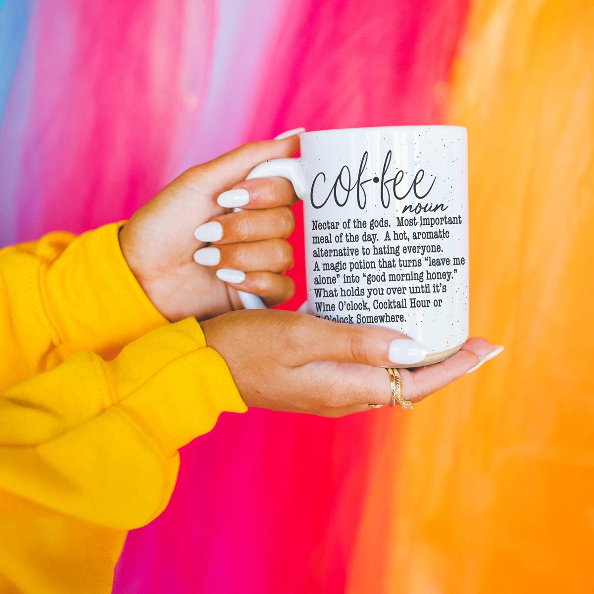 Person holding a mug with 'coffee' definition text against a colorful background