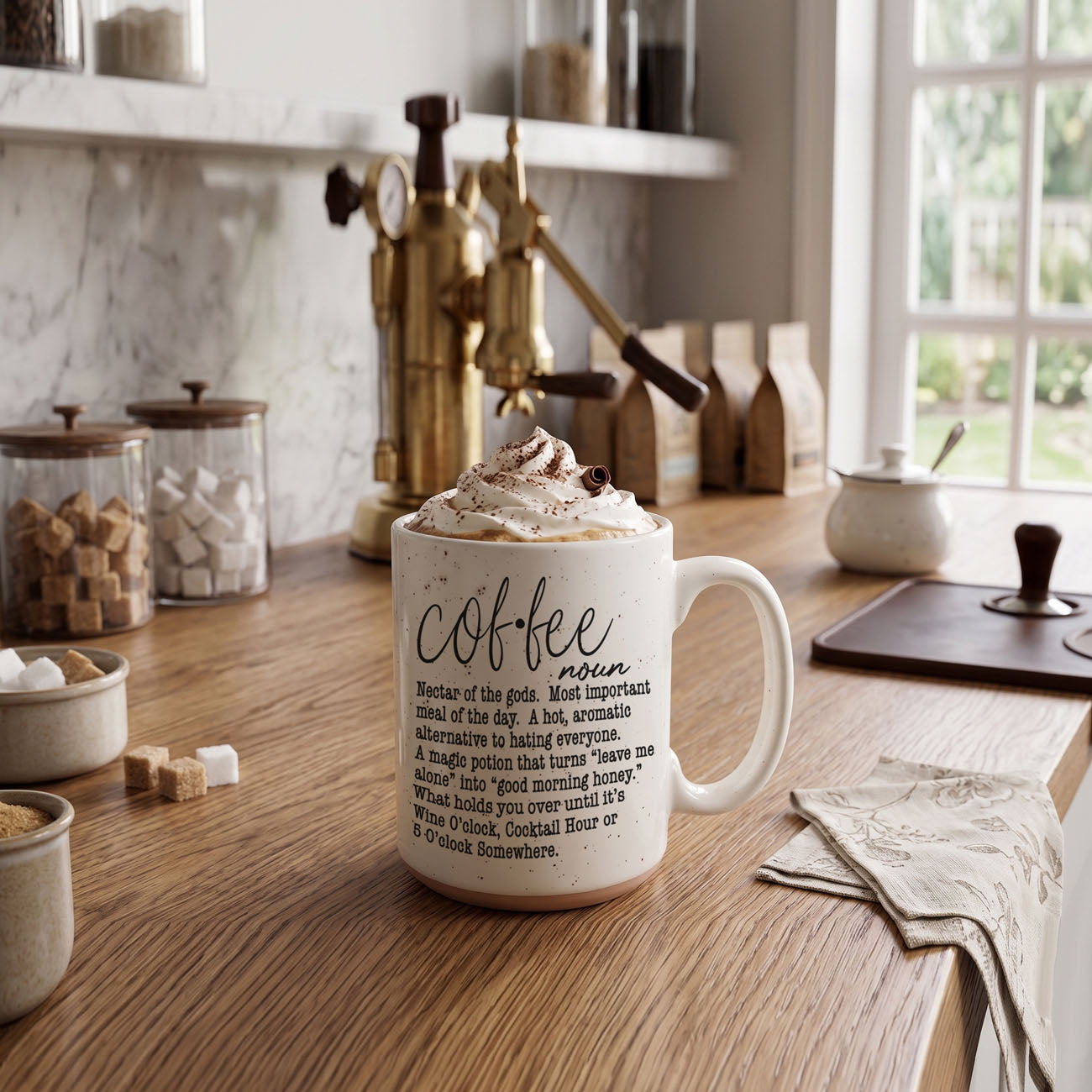 White mug with coffee definition text on a kitchen counter with coffee-making equipment.