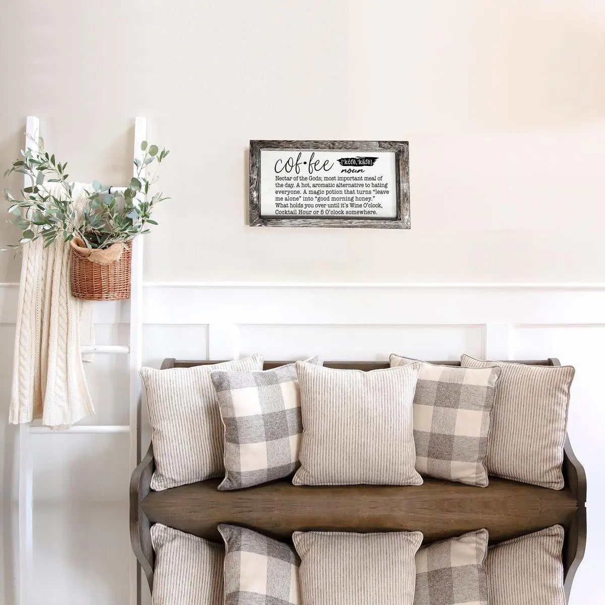 Nestled nook with a wooden bench featuring plaid and striped cushions, a 'Coffee' sign on the wall, and a plant.