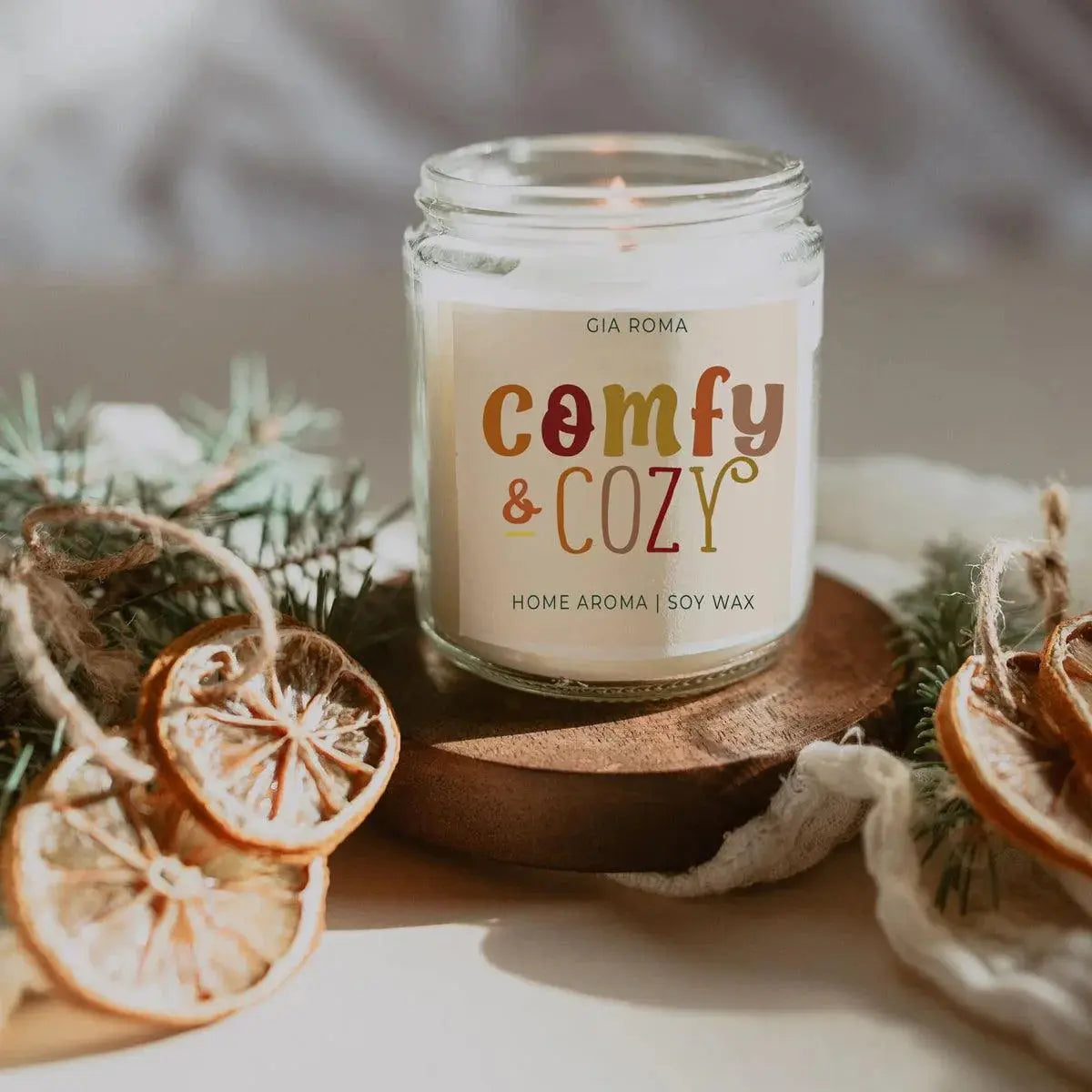 Candle labeled 'comfy & cozy' with decorative elements on a neutral background