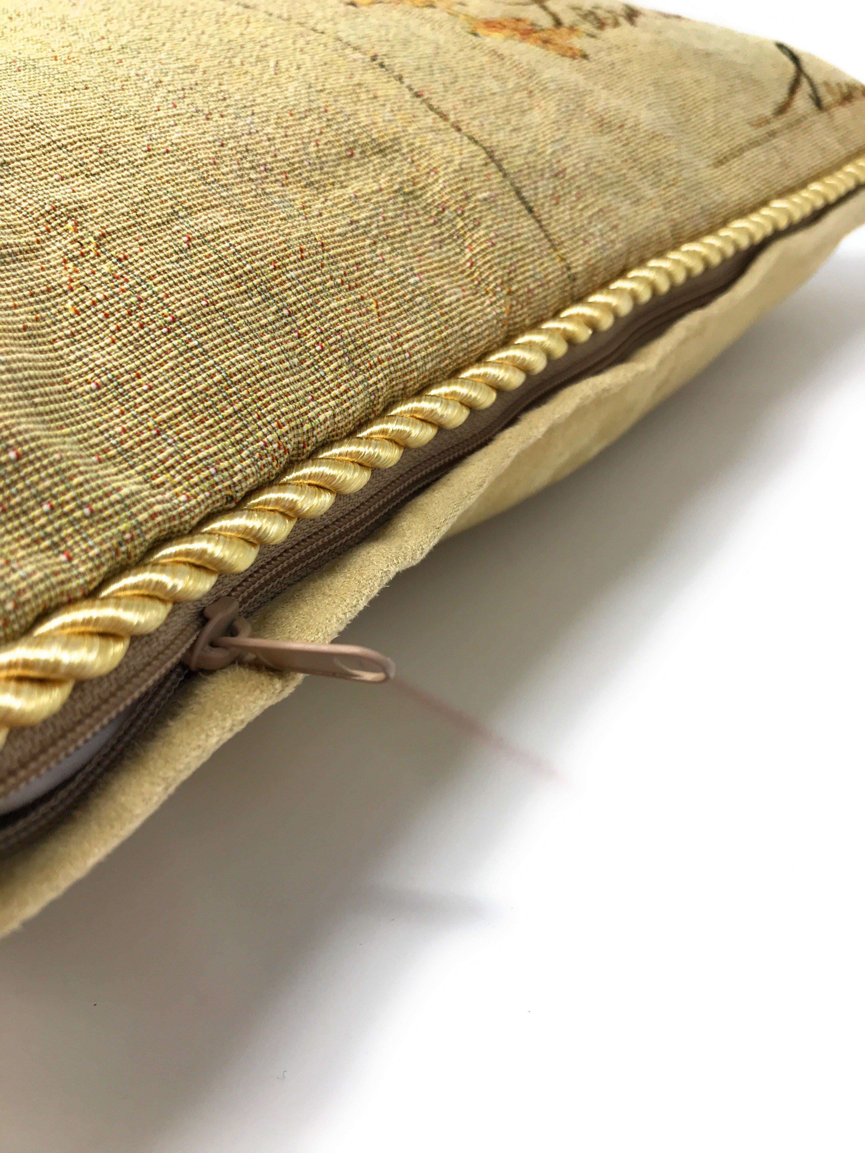 Close-up of a textured gold pillow with braided trim on a light background