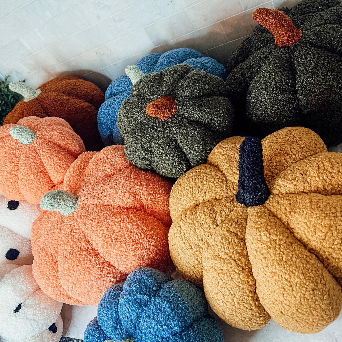 Collection of textured pumpkins in various colors on a white surface