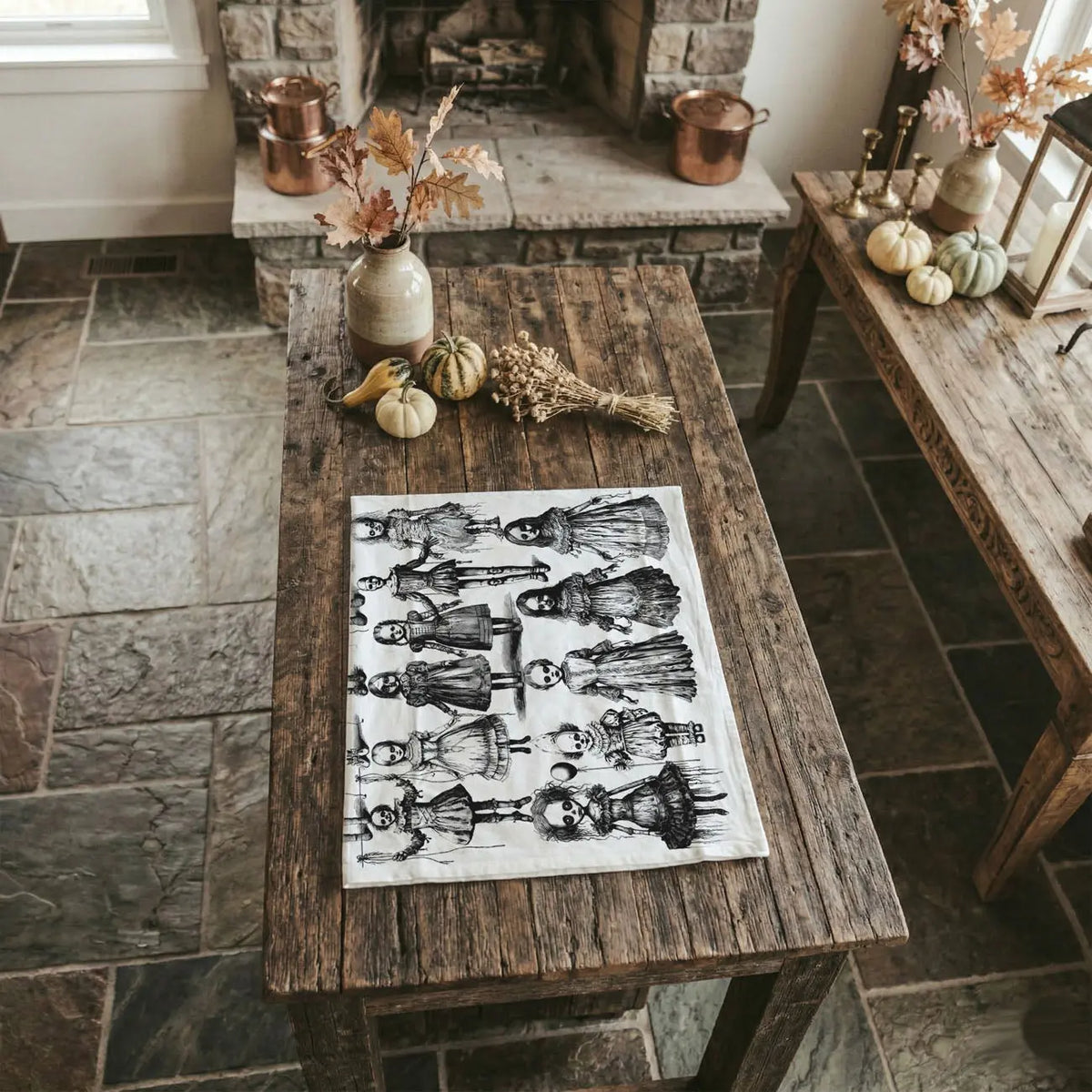 Decorative table setting with a black and white patterned tablecloth, pumpkins, and decorative items in a rustic kitchen.