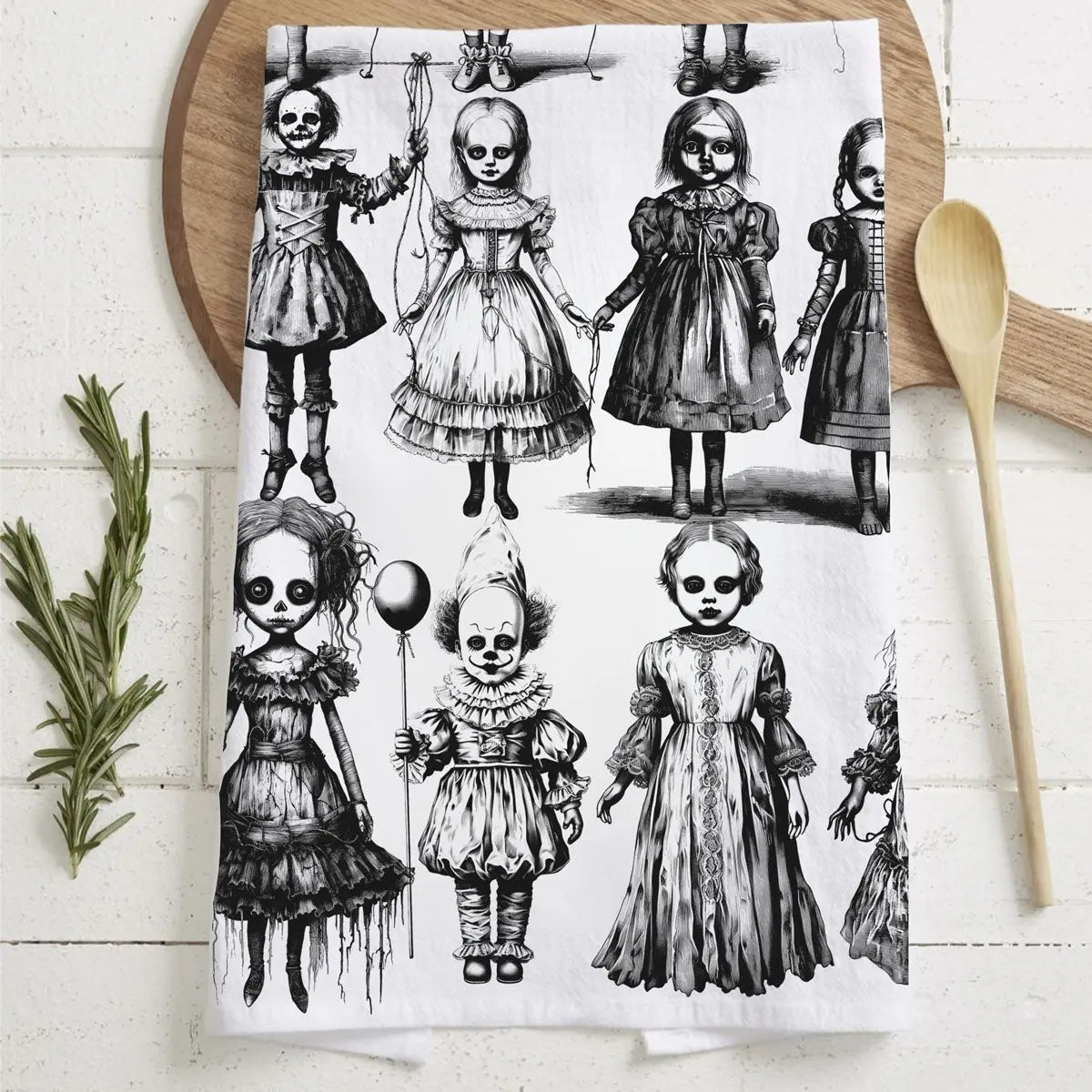 Tea towel with black and white illustrations of dolls on a wooden board.
