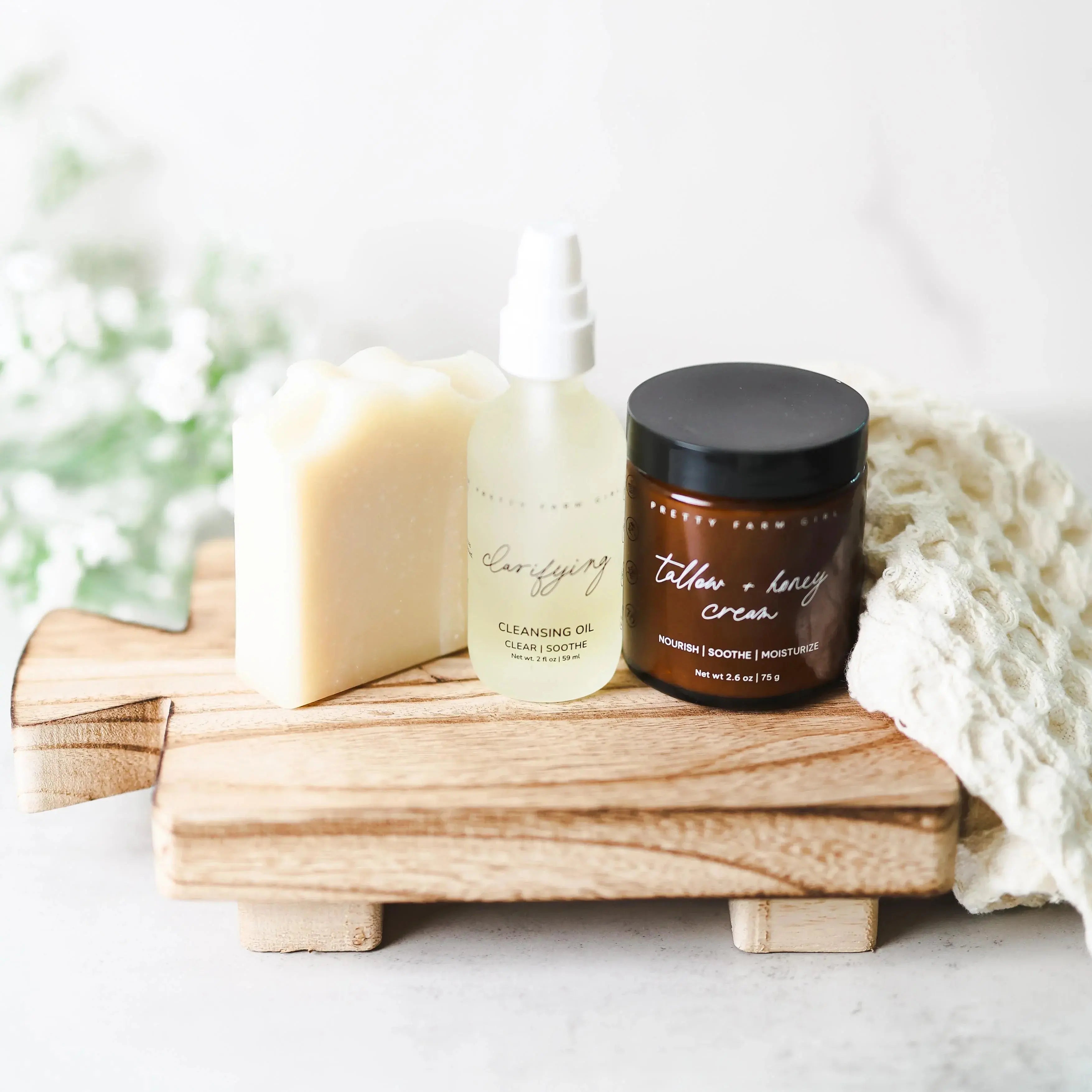 Cozy farmhouse bath essentials: soap bar, clarifying cleansing oil, tallow honey cream on rustic wood