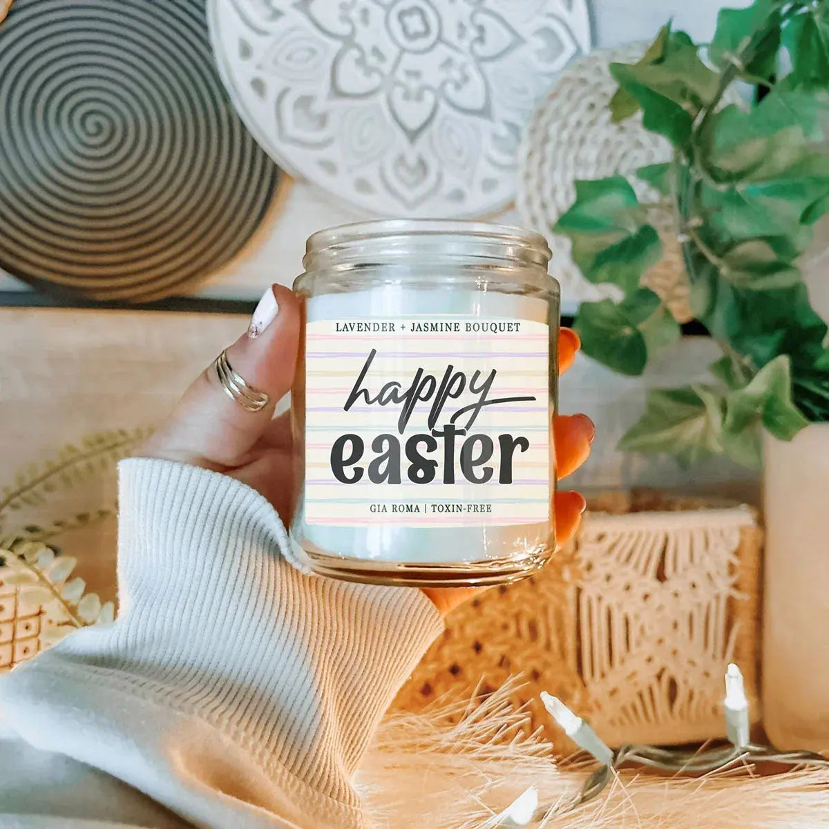Hand holding a 'Happy Easter' candle with decorative background