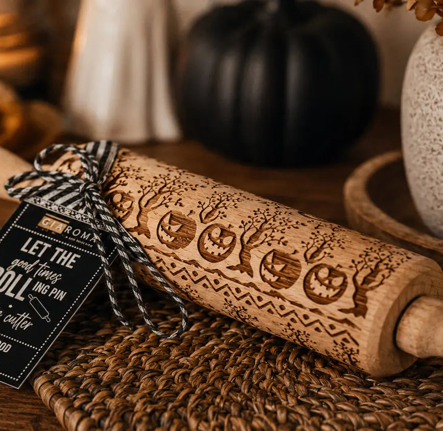 Wooden embossing rolling pin with Halloween designs on a textured surface, tied with twine and a tag.