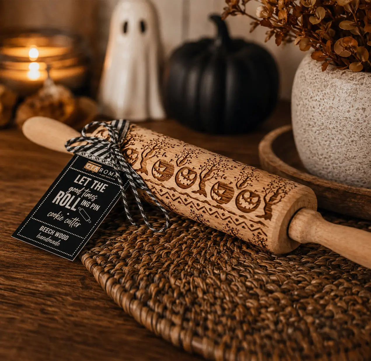Wooden rolling pin with Halloween designs on a textured surface, surrounded by decorative items.