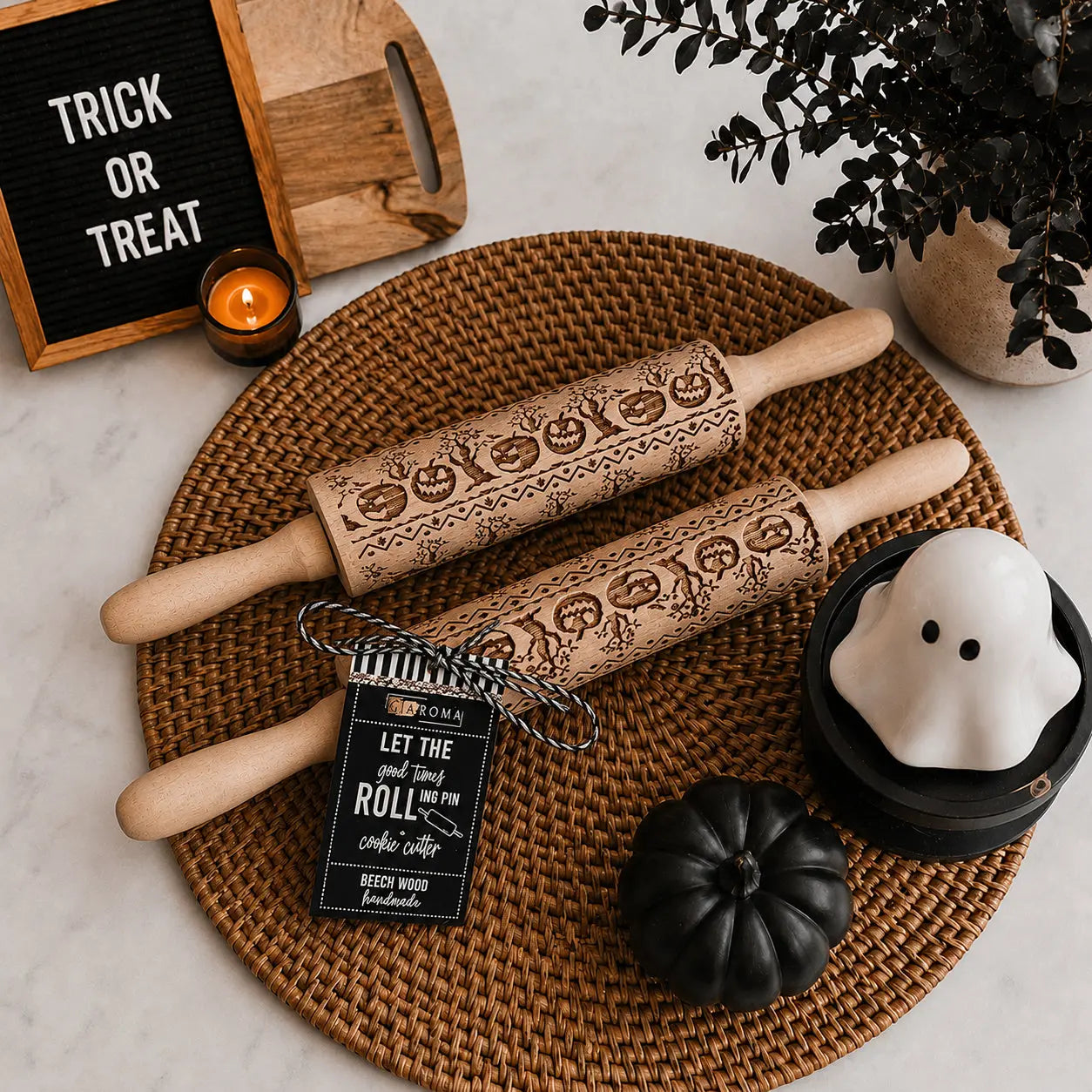 Two Halloween-themed rolling pins on a woven mat with decorative items.