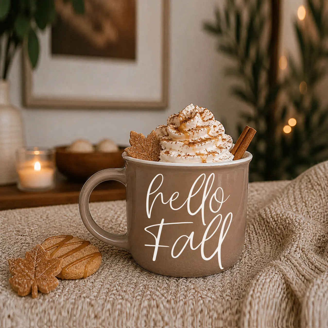 Brown mug with 'hello Fall' text, topped with whipped cream and cookies, on a textured surface.